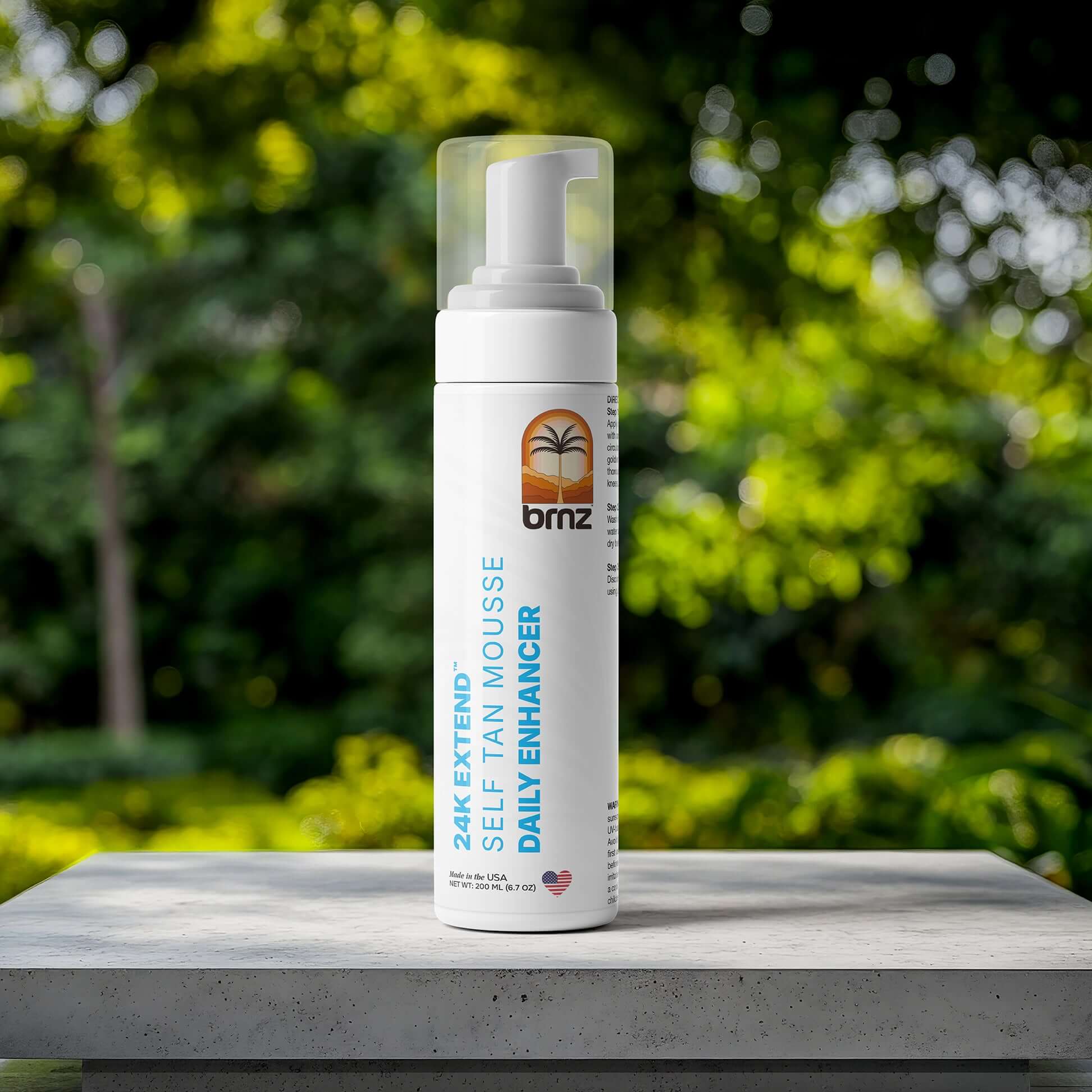 24K Extend self-tanner mousse bottle surrounded by lush greenery for glowing skin and hydration.